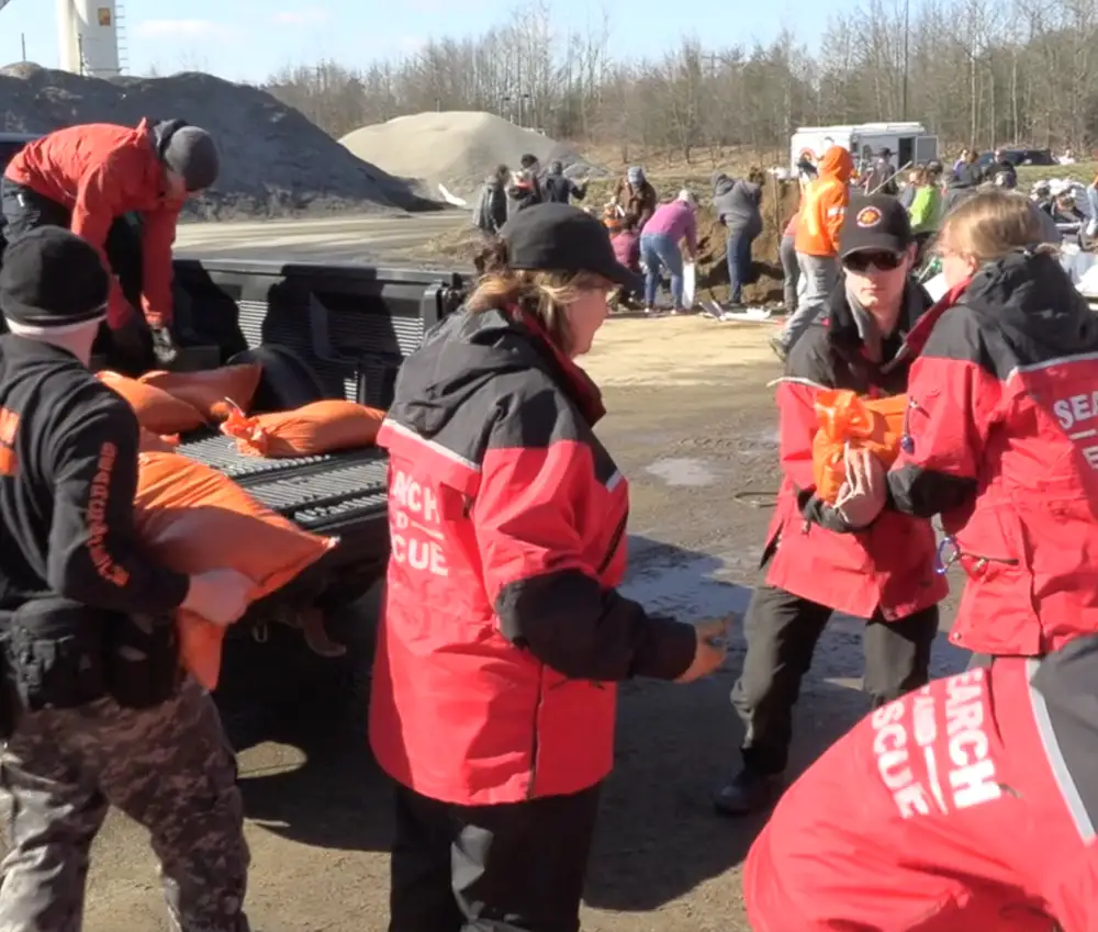 Volunteers filling sandbags and piling them onto a truck